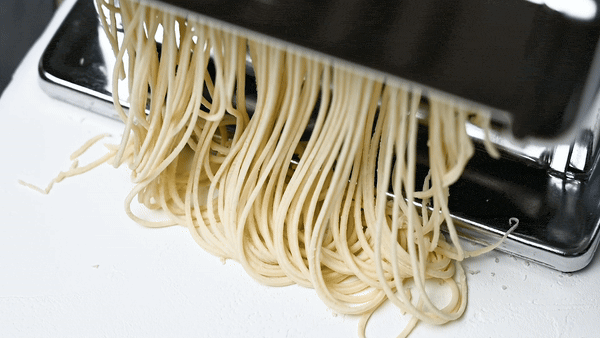 a gif showing ramen noodles being cut with cutting attachment on a pasta machine