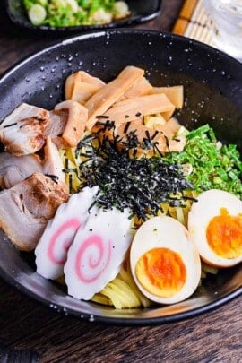 Abura soba soupless ramen in a black bowl topped with ramen egg, narutomaki, menma, chashu, green onion and kizami nori