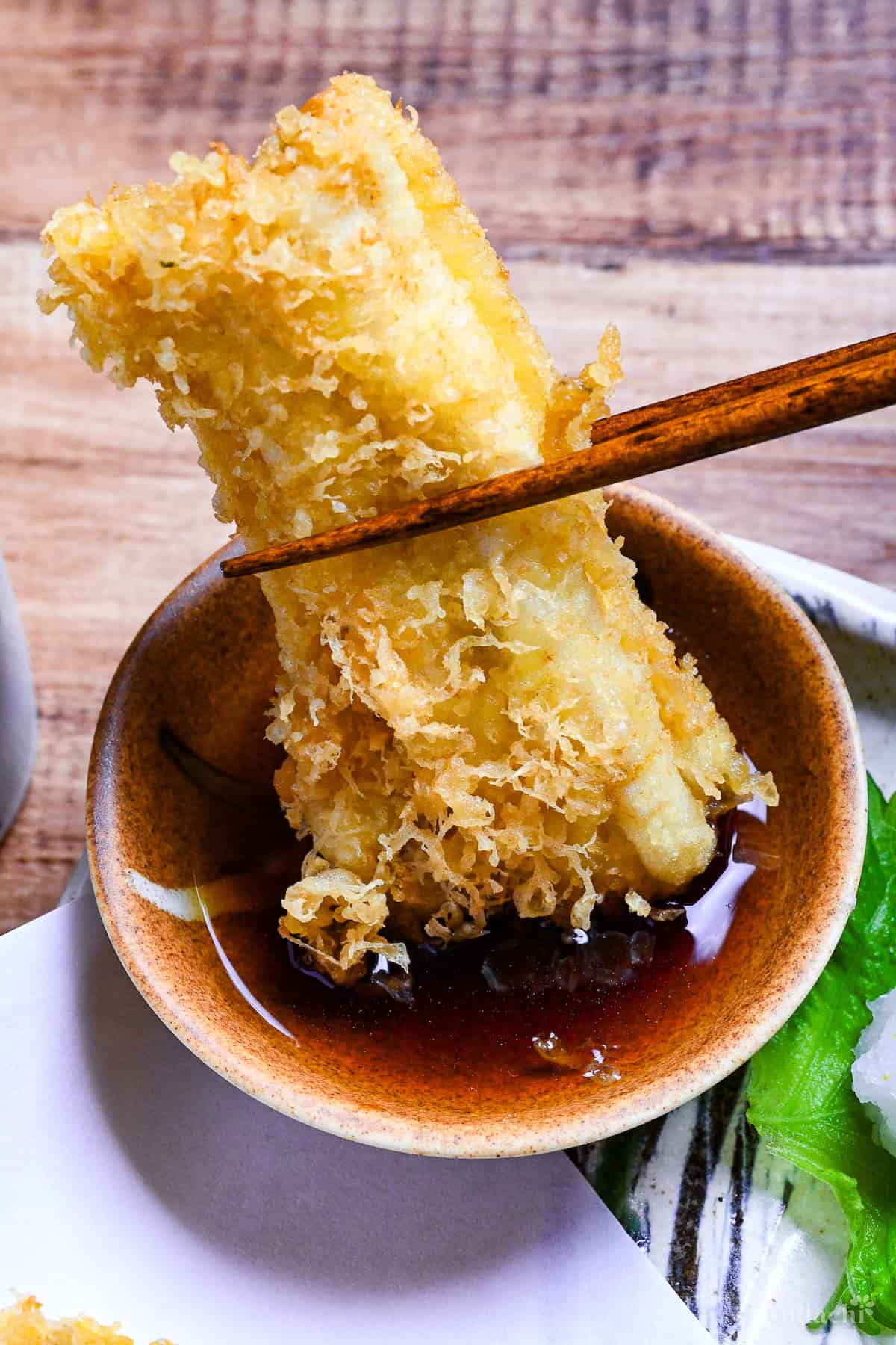 Dipping tempura conger eel in tempura dipping sauce