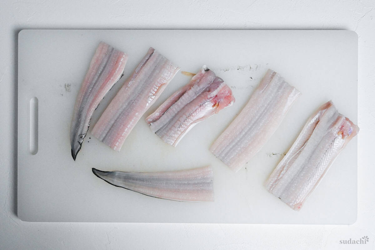 conger eel cut into pieces on a white chopping board ready for tempura