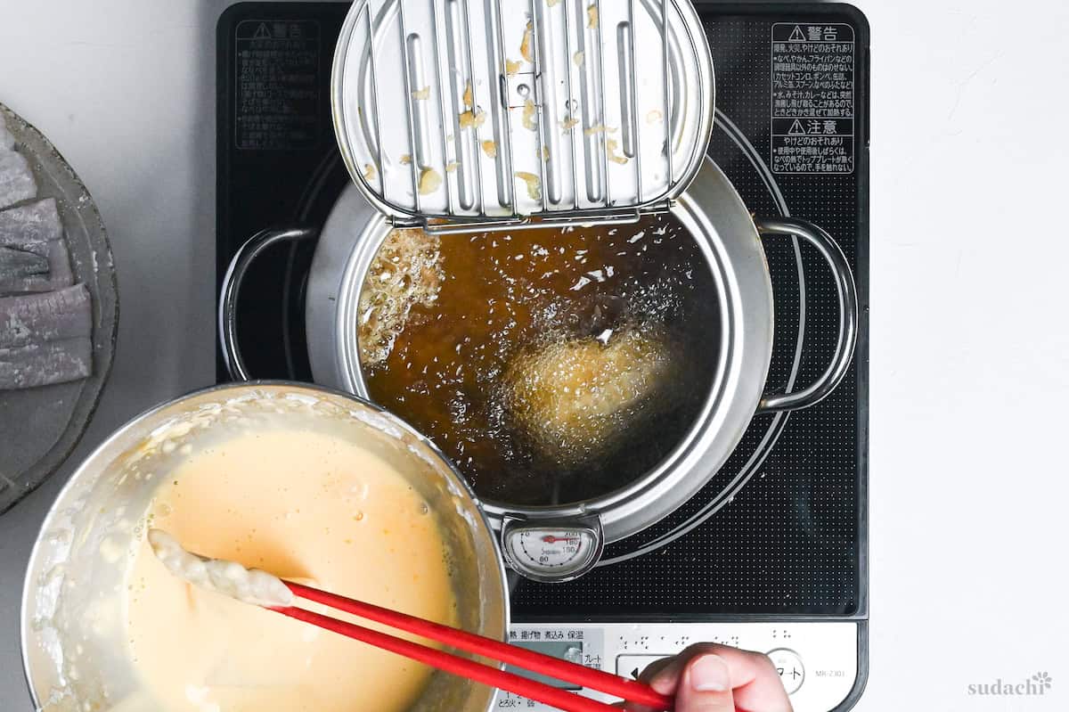 placing tempura battered conger eel in pot of oil