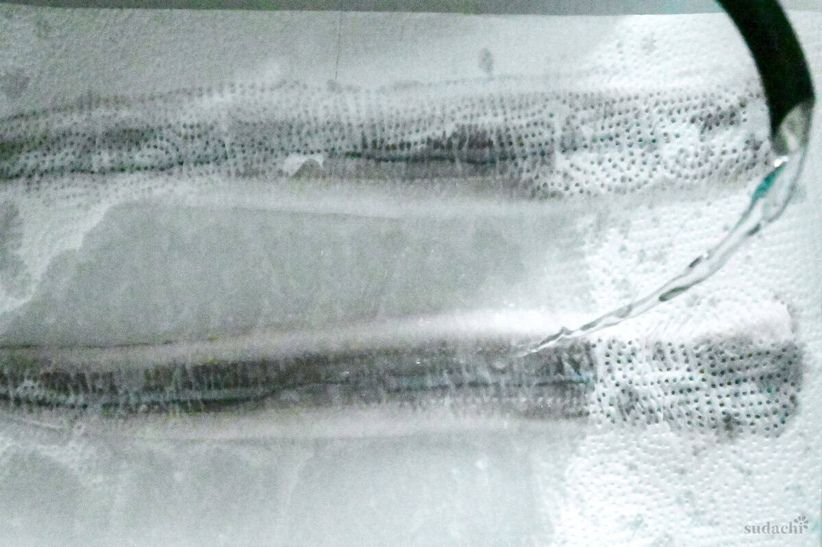 pouring boiling water over conger eels covered with kitchen paper