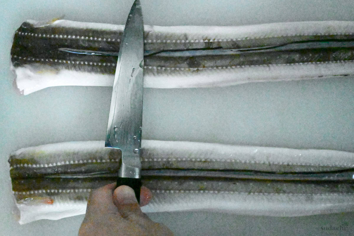 scraping slime off of raw conger eels using the back of a knife