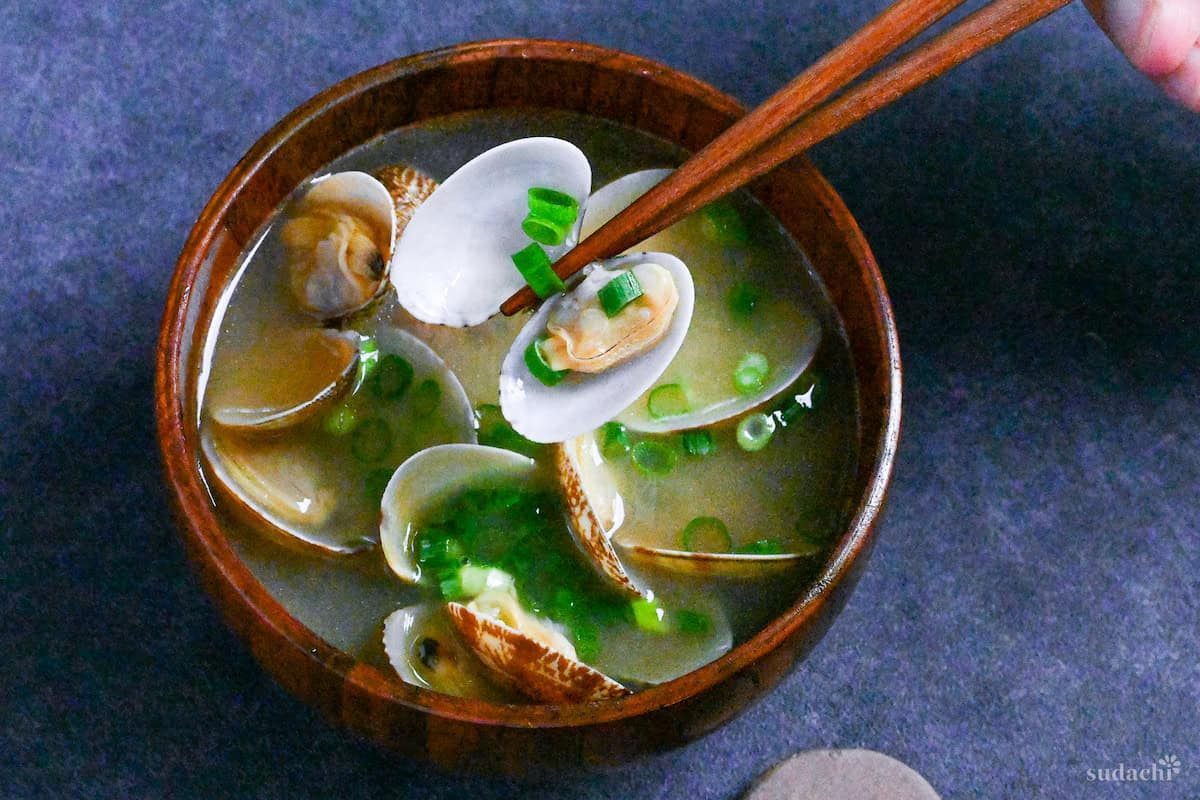 Asari clam miso soup in a wooden bowl on a dark gray background