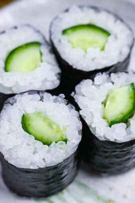 4 kappa maki (cucumber sushi rolls) on a gray plate with green brush effect close up