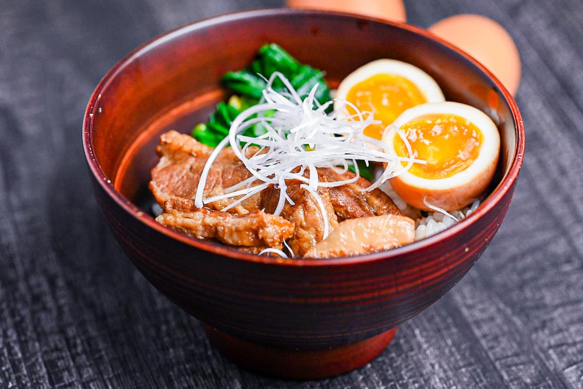 buta no kakuni served over rice with soft boiled marinated eggs and mustard spinach