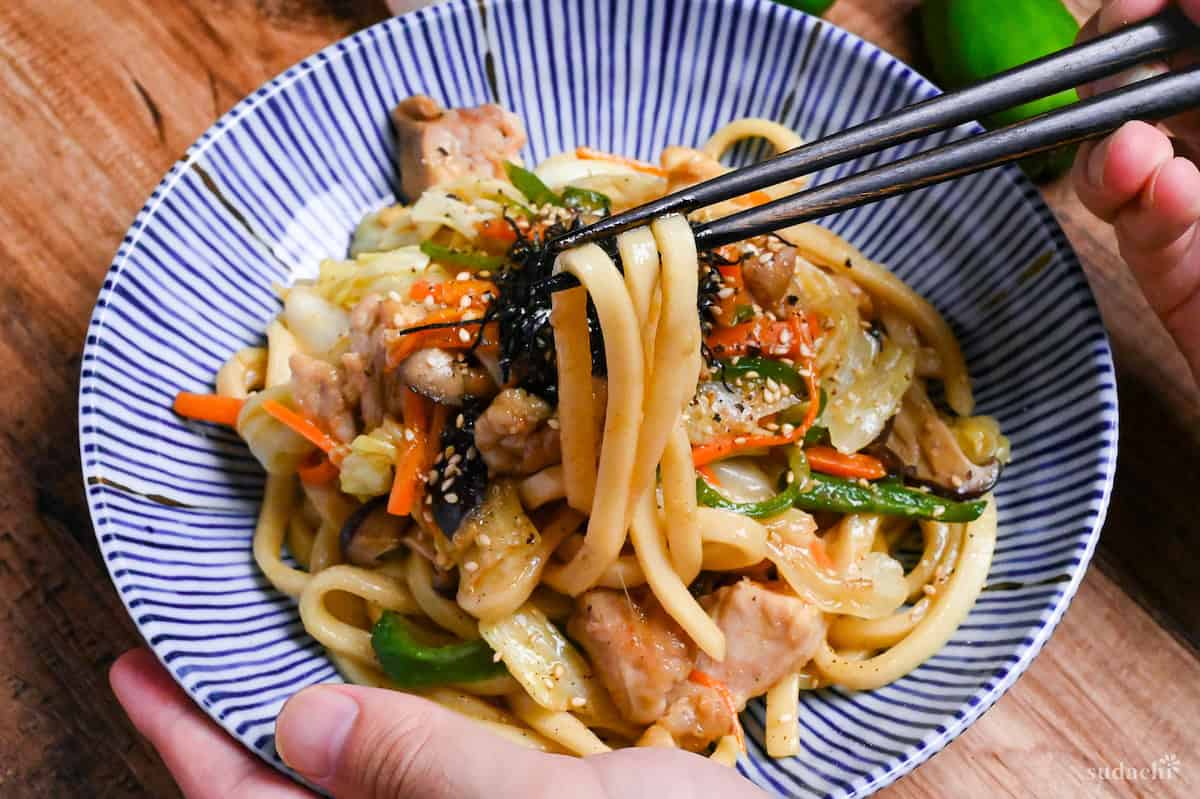 holding chicken butter shoyu yaki udon with chopsticks