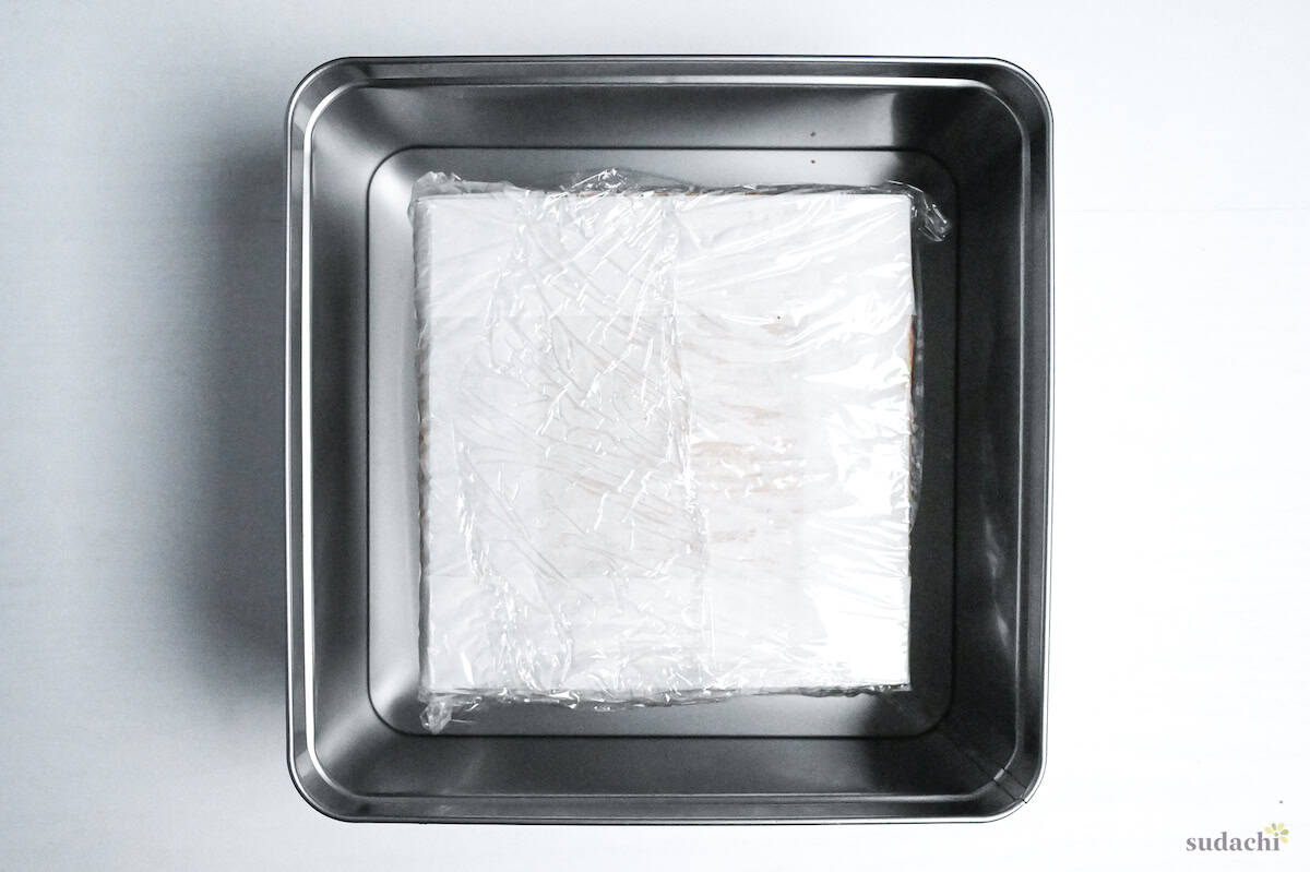 Japanese castella cake wrapped with plastic wrap and placed in a large airtight container