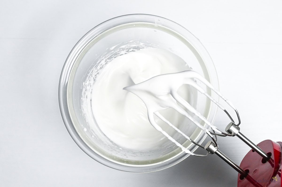 meringue with stiff peaks in a glass mixing bowl