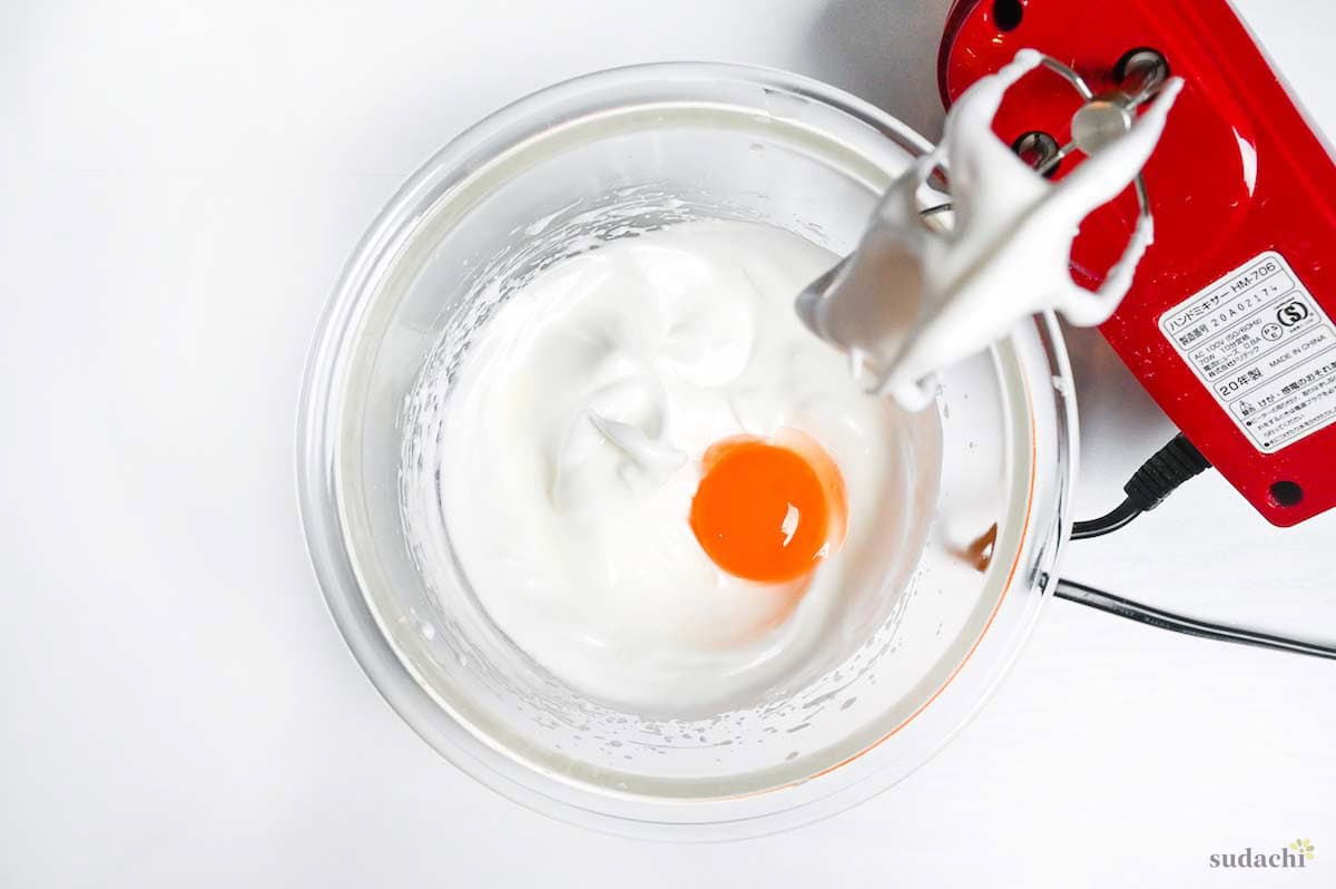 adding egg yolks to a glass mixing bowl