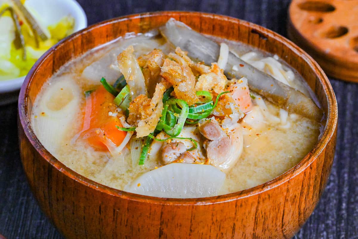 Japanese Chicken Miso Soup (Torijiru) in a wooden bowl topped with green onion and strips of crispy chicken skin