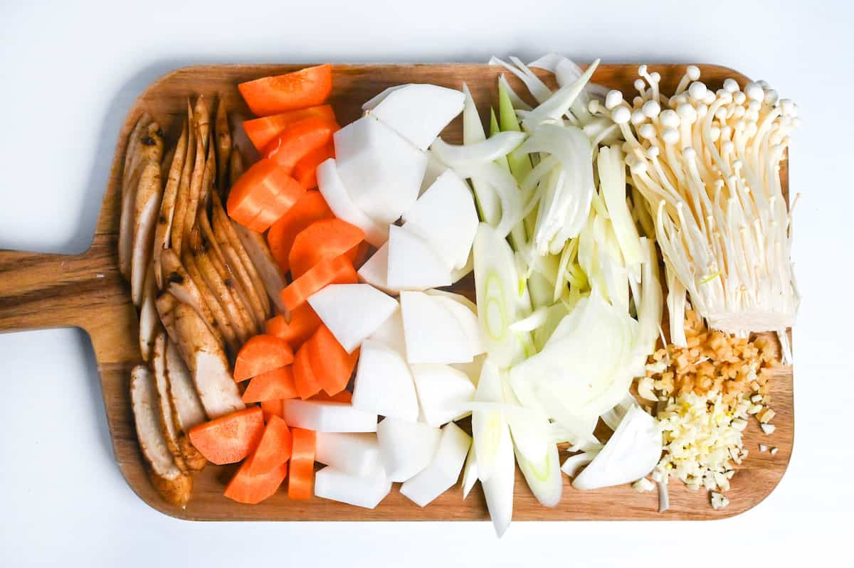 vegetables used to make chicken miso soup chopped up on a wooden chopping board