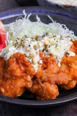final plating of chicken nanban with shredded cabbage, tomato wedges and tartar sauce