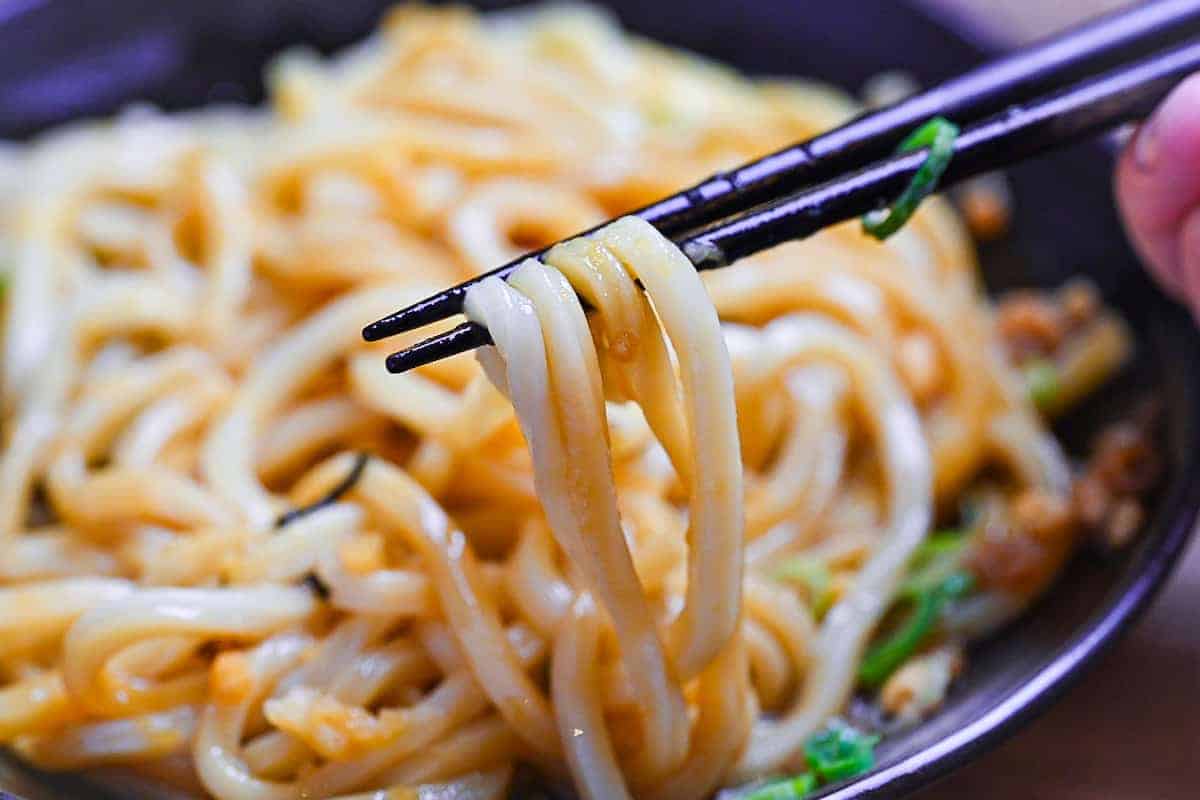 lifting mixed udon with black chopsticks
