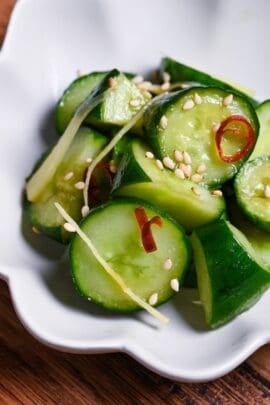 Complete Japanese pickled cucumber with ginger and chili sprinkled with sesame seeds in a small white serving dish