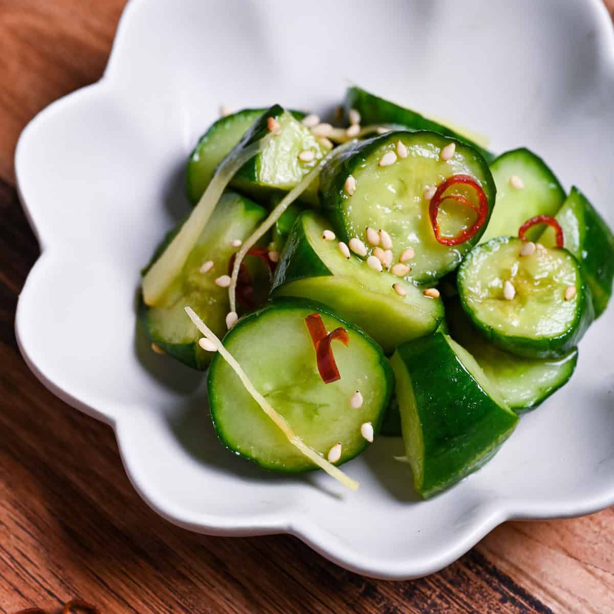 Complete Japanese pickled cucumber with ginger and chili sprinkled with sesame seeds in a small white serving dish