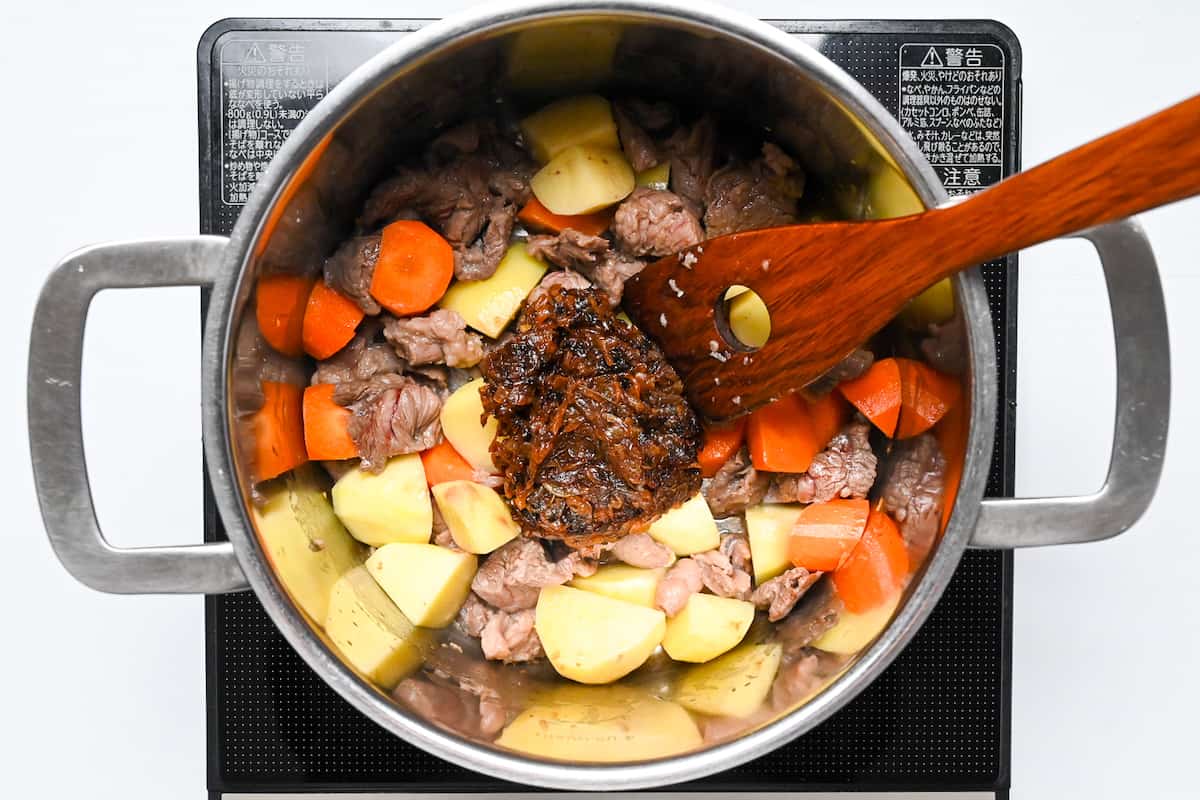 Caramelized onions added to a pot with beef, potato and carrot