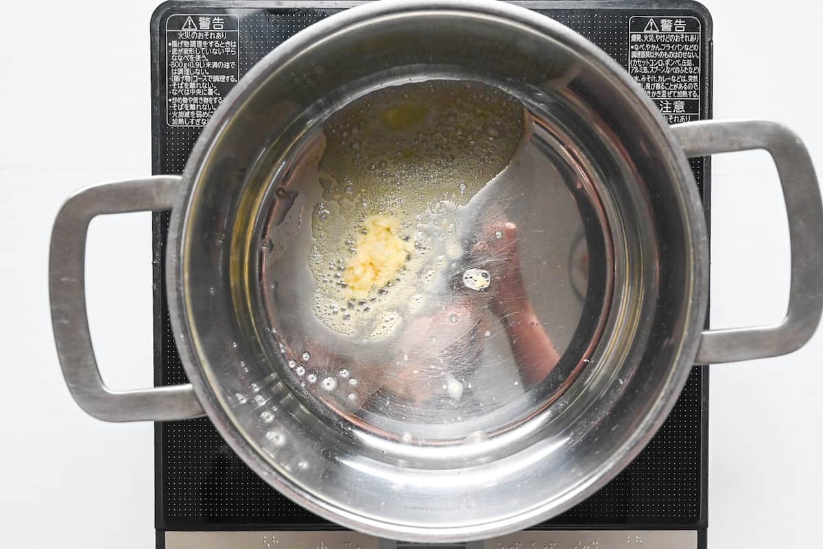 Crushed garlic frying in butter in a large silver pot