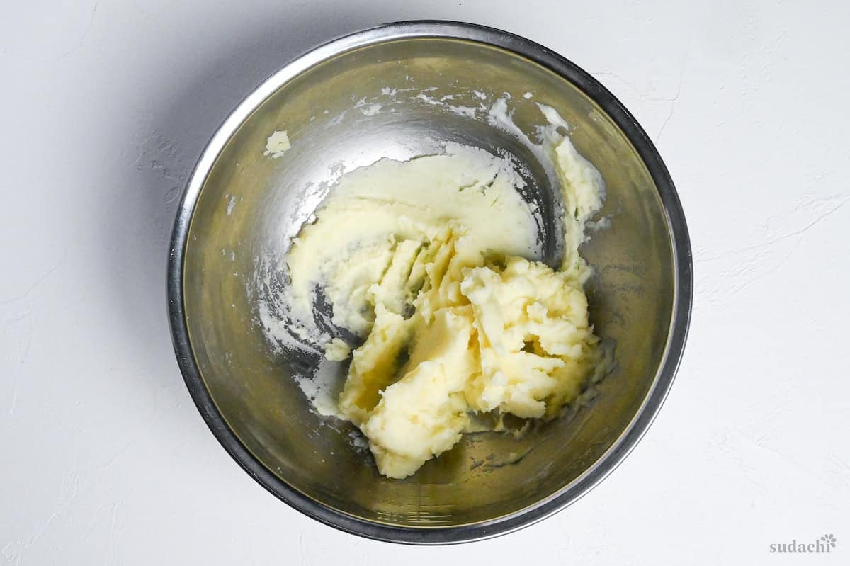 creamy mashed potatoes in a mixing bowl on a white background