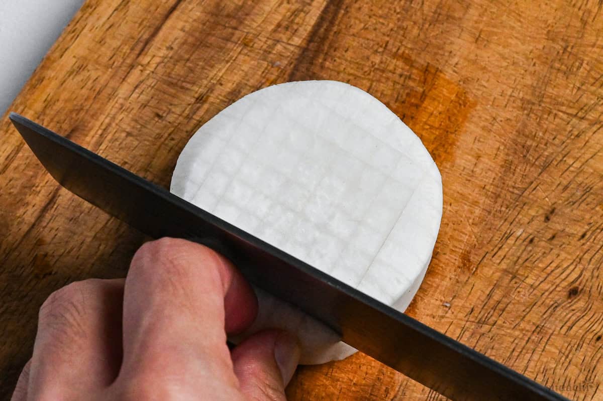 close up of cutting a cross hatch pattern on daikon radish round