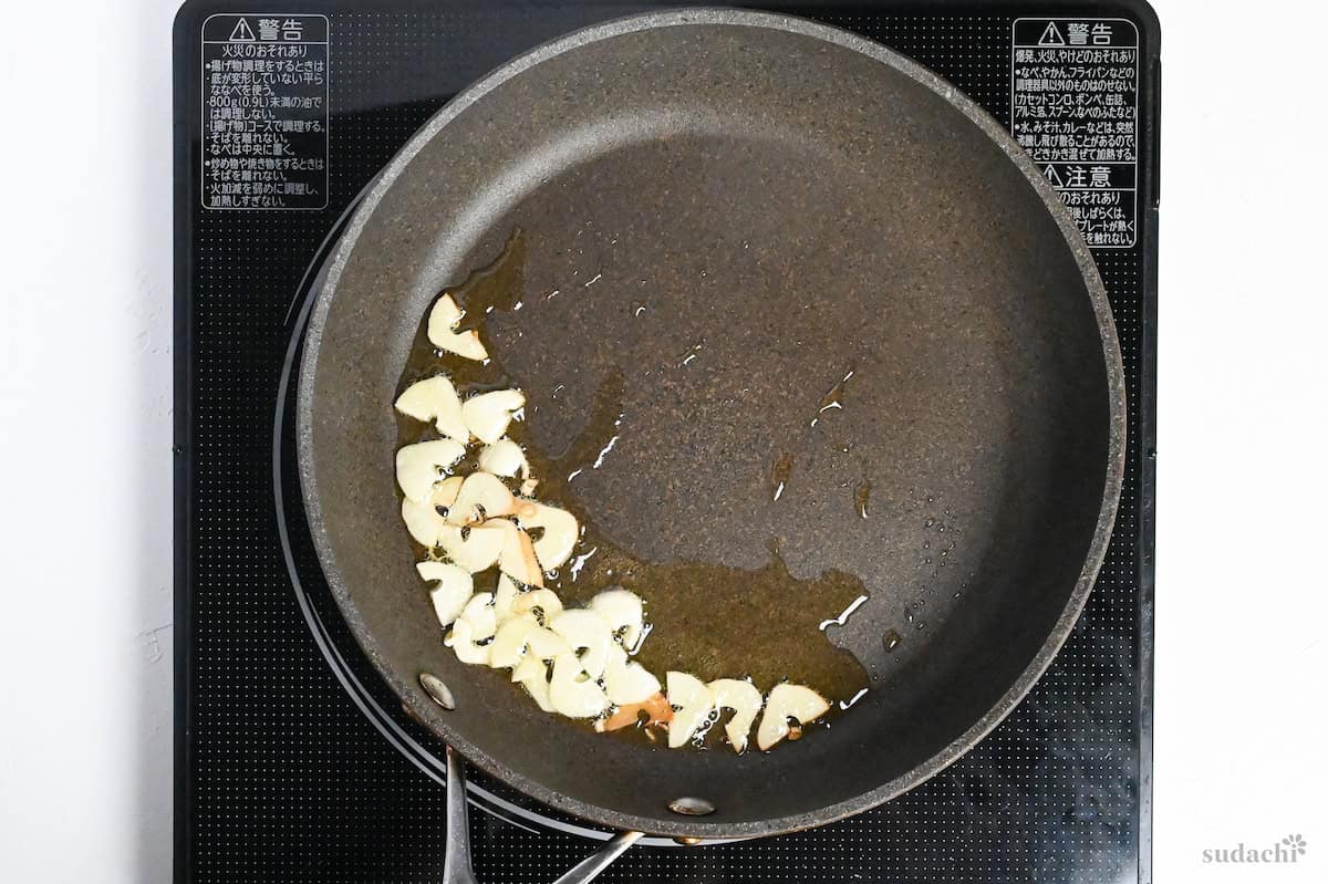 frying garlic slices in a pan with oil to make crispy garlic topping
