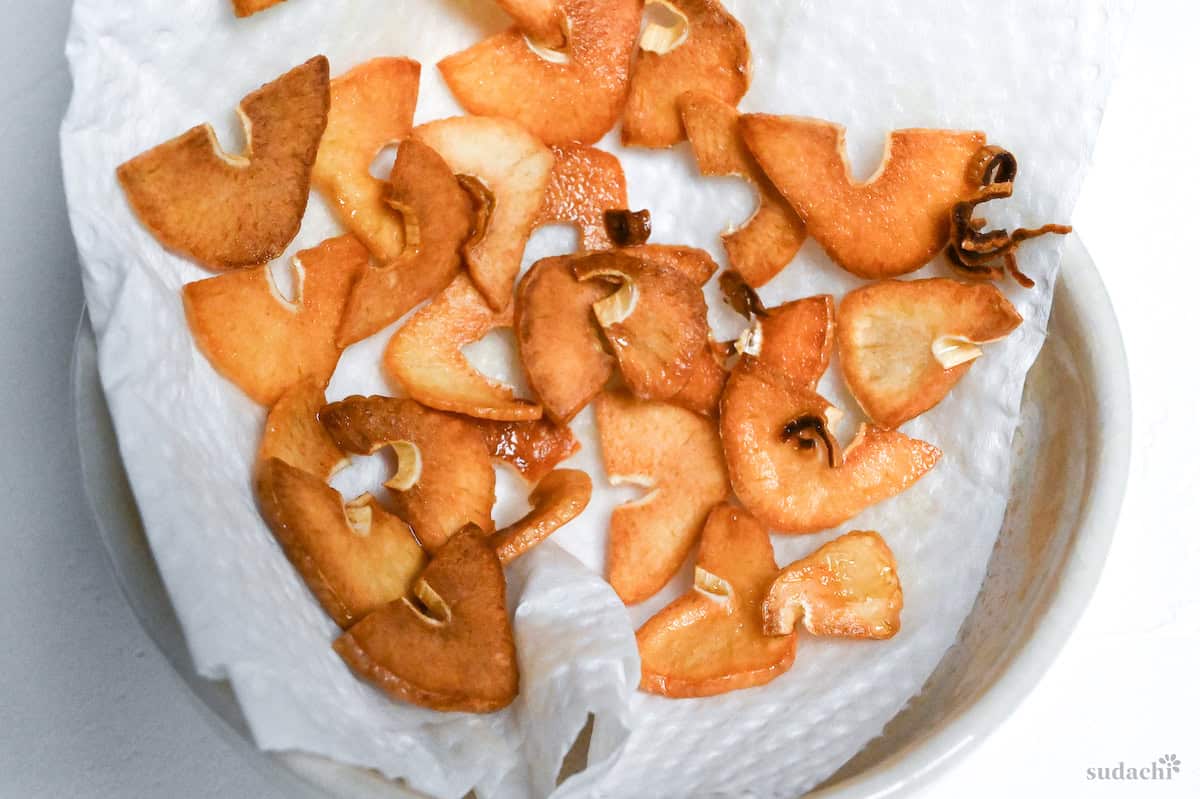 close up of crispy garlic slices draining on kitchen paper