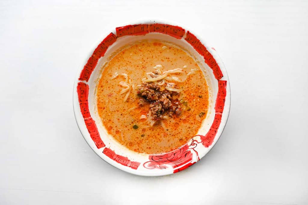 adding meat and noodles to tantanmen broth