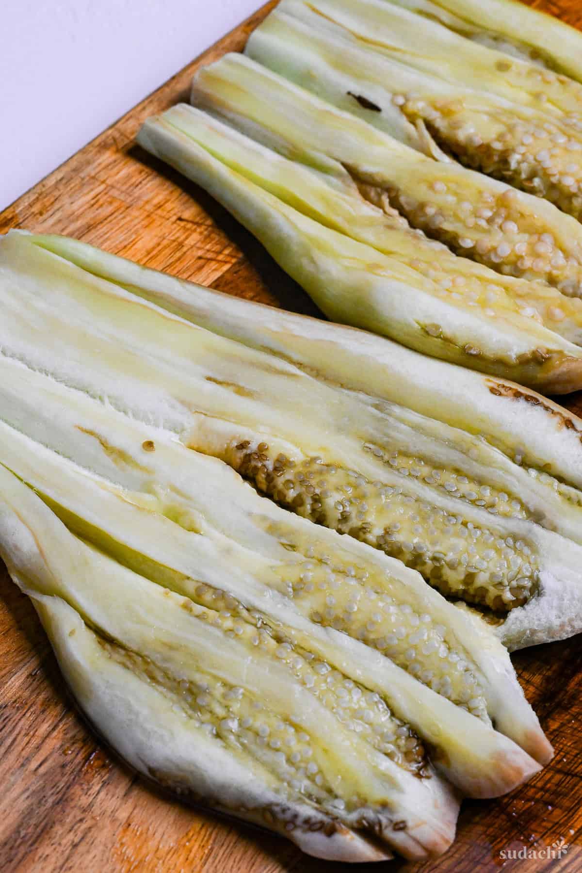 3 flattened eggplants on a wooden chopping board