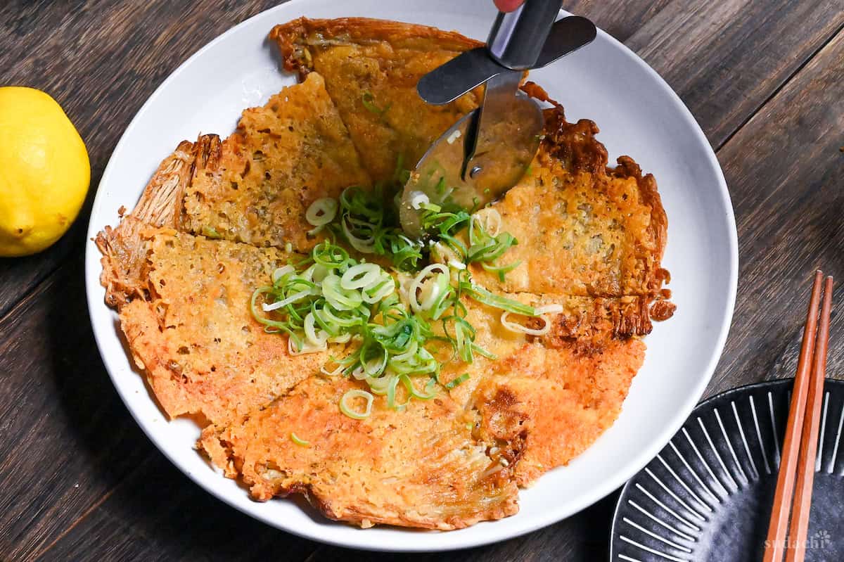 Cutting crispy enoki cheese into triangles using a pizza cutter