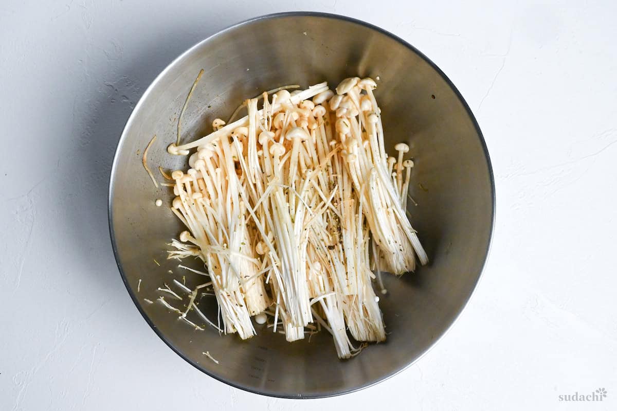 enoki mushrooms sprinkled with dried mixed herbs in a mixing bowl
