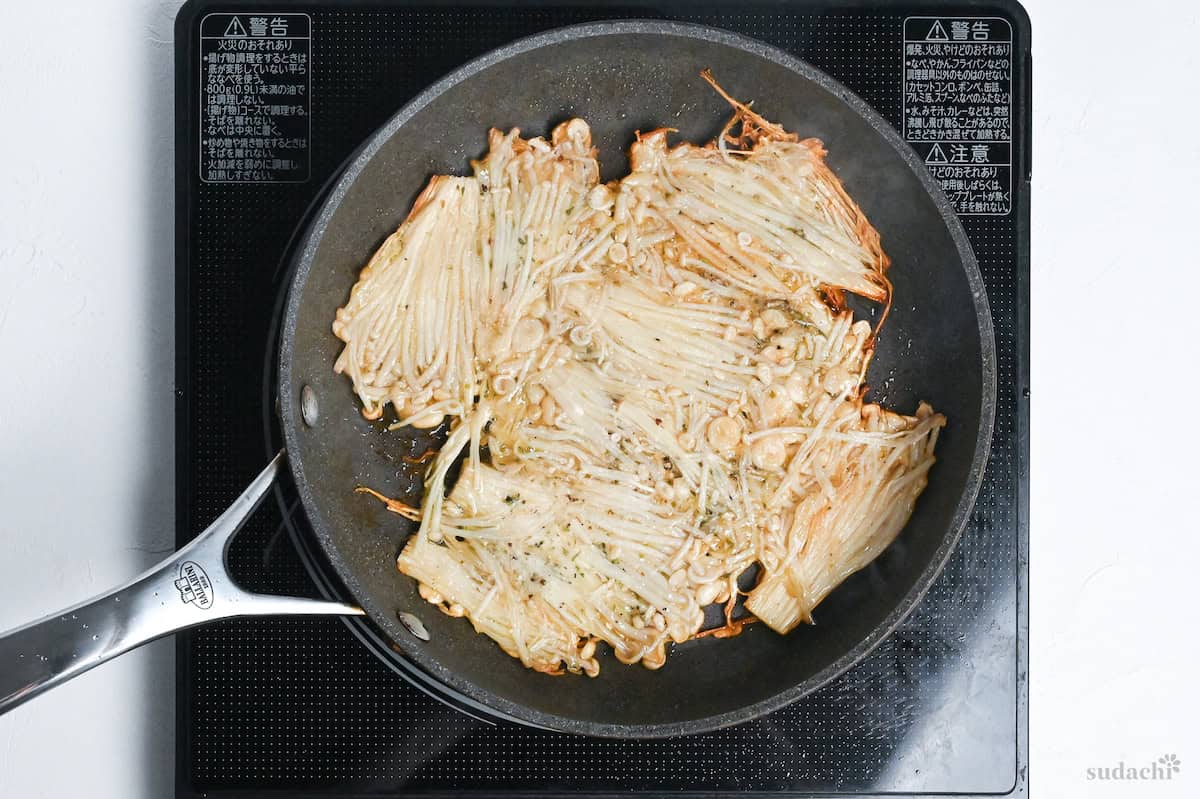 crispy enoki mushrooms in a frying pan on the stove top