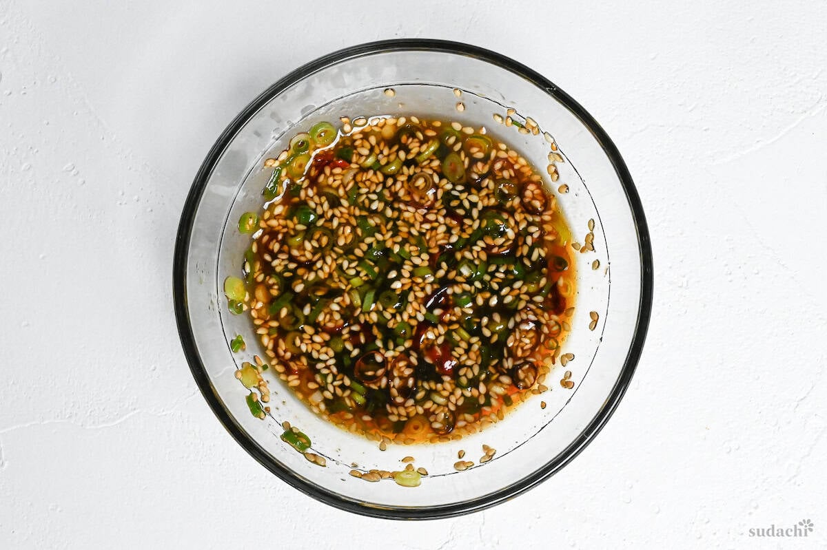 Tangy soy sauce and vinegar based sauce for enoki mushroom donburi in a glass bowl on a white background