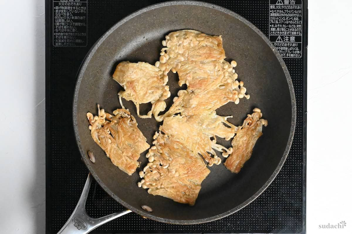 browned and crispy enoki mushrooms in a frying pan