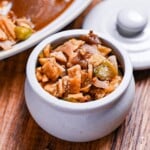 Homemade fukujinzuke (Japanese pickles for curry) in a small ceramic pickle pot next to a plate of curry rice