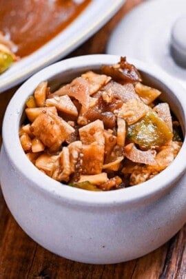 Homemade fukujinzuke (Japanese pickles for curry) in a small ceramic pickle pot next to a plate of curry rice