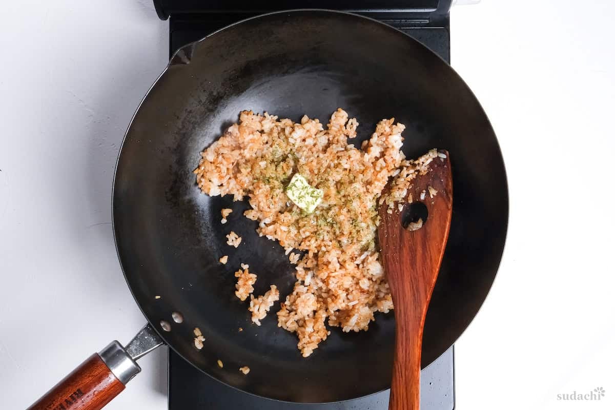 butter and parsley added to garlic fried rice in a pan