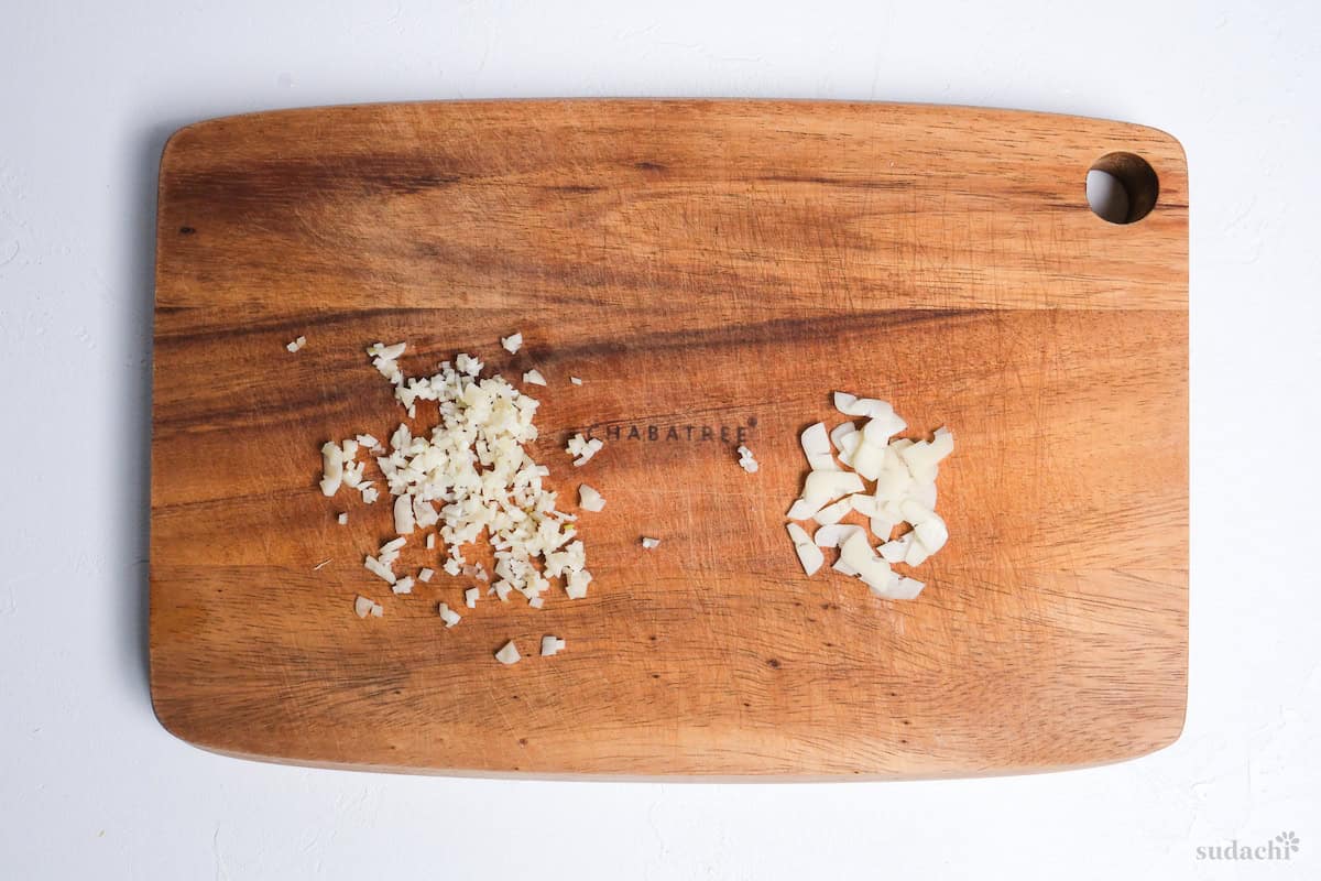 finely diced garlic and thinly sliced garlic on a wooden cutting board