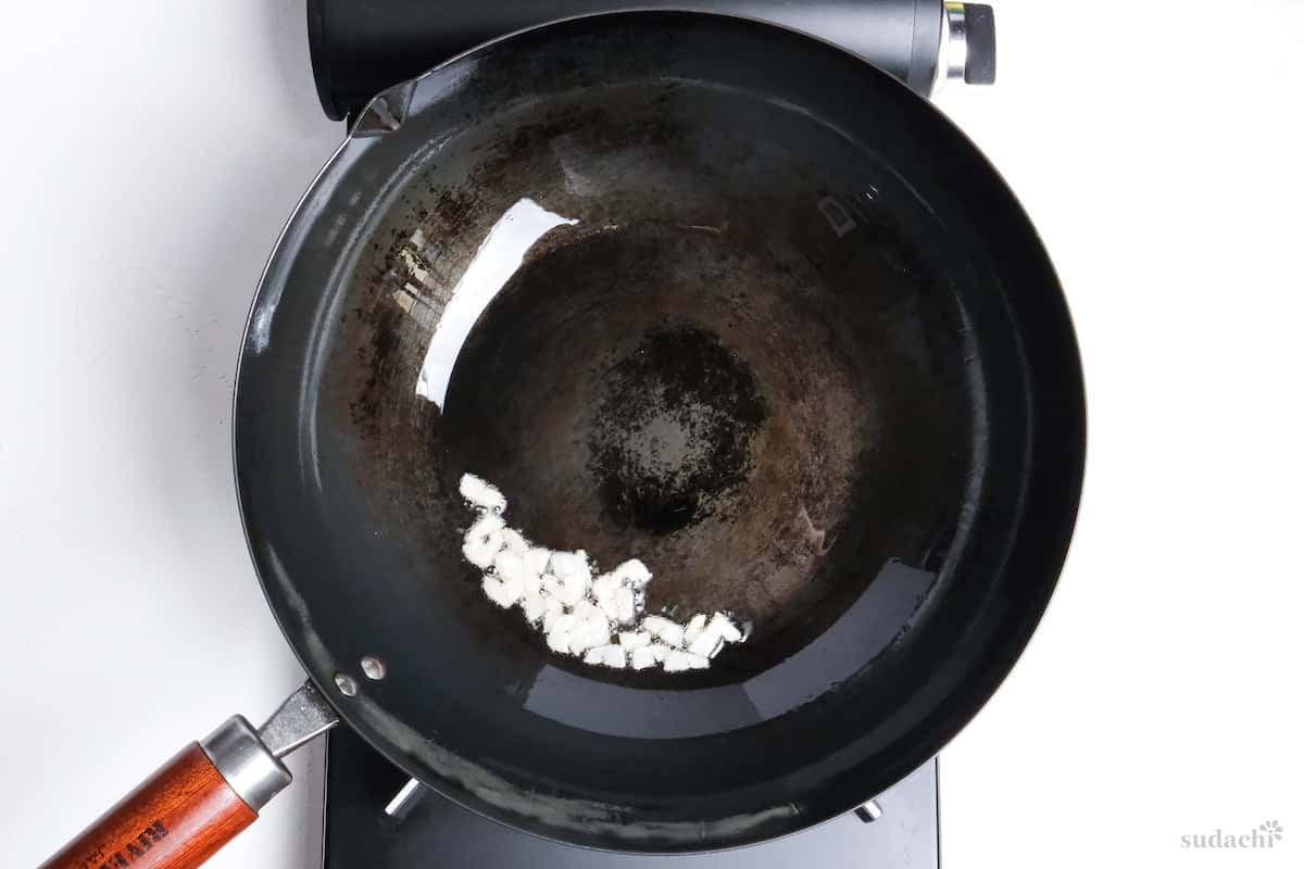 thin garlic slices sizzling in oil in a wok