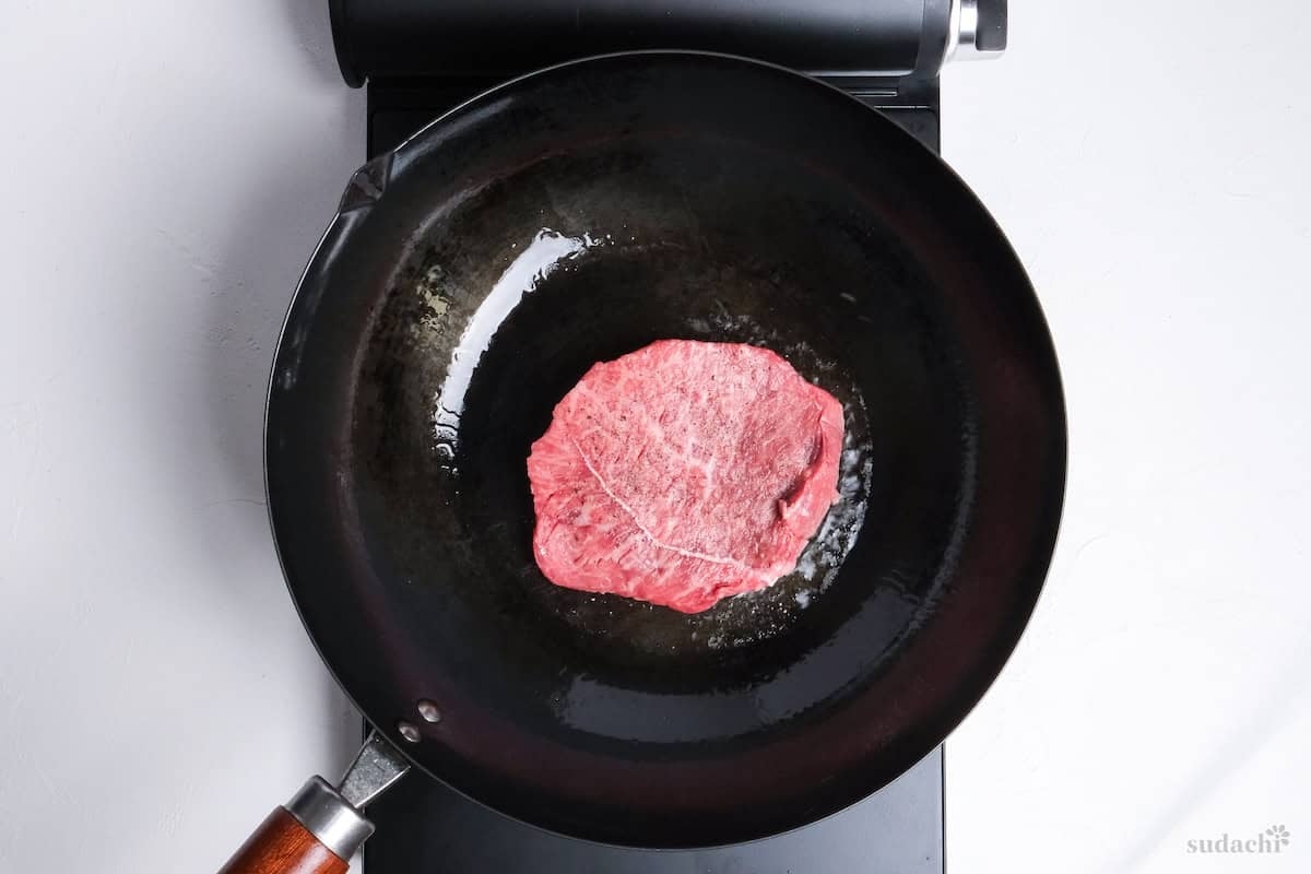 frying a thick fatty steak in a wok