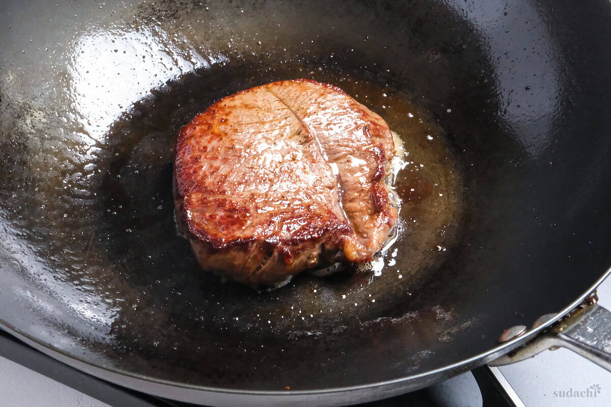 fried beef steak in a wok side view to show seared edges