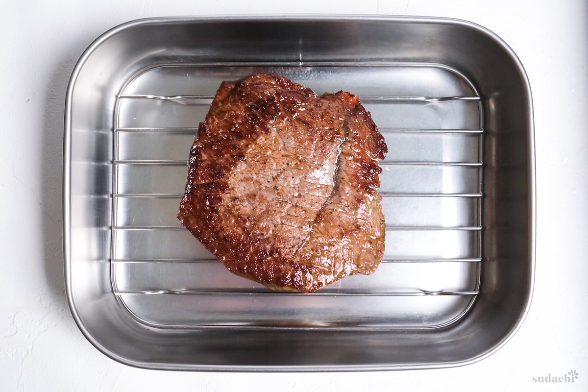 pan-seared beef steak resting on a wire rack