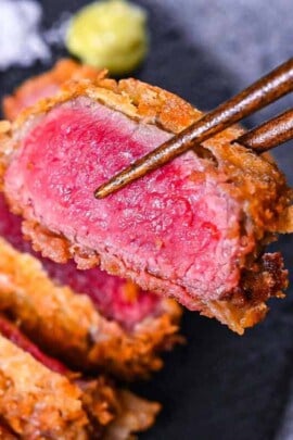 Gyukatsu (Japanese beef steak cutlet) served with cabbage, salt flakes and wasabi on a black slate plate