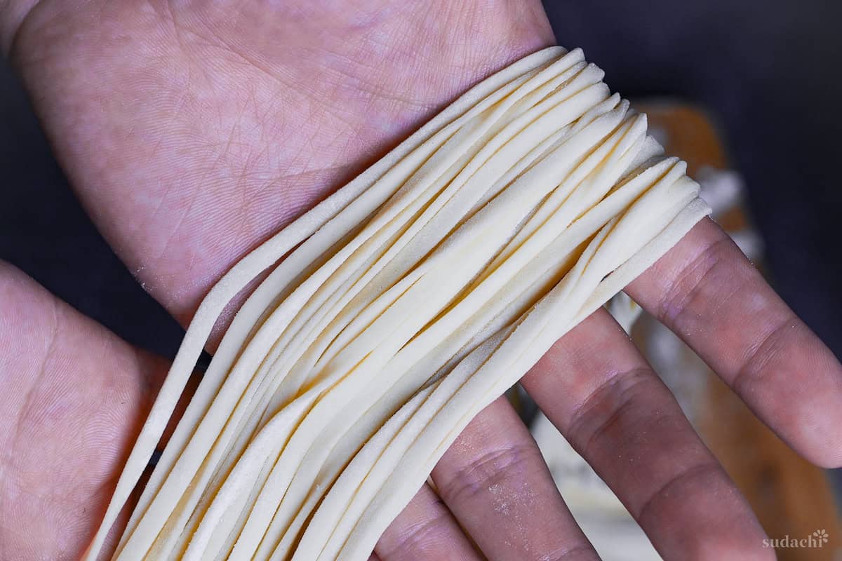 holding homemade udon noodles in hand