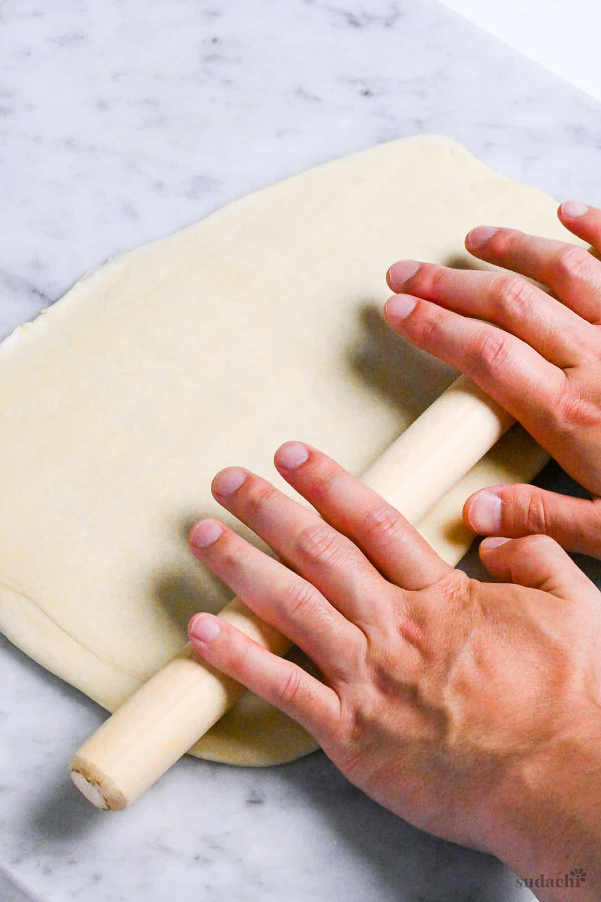 rolling dough for handmade ramen noodles with wooden rolling pin