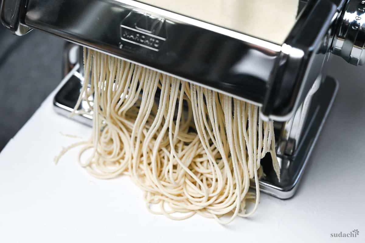 ramen noodles being cut using a cutting attachment on a pasta machine