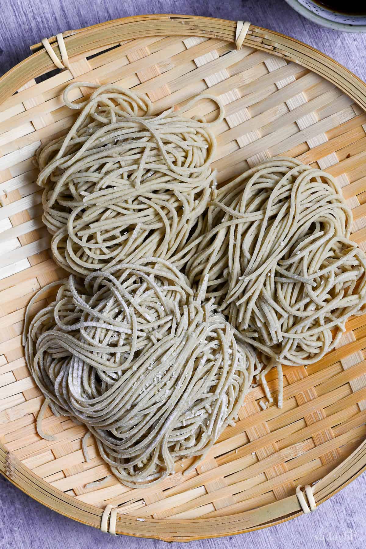 three bundles of homemade soba noodles on a bamboo tray