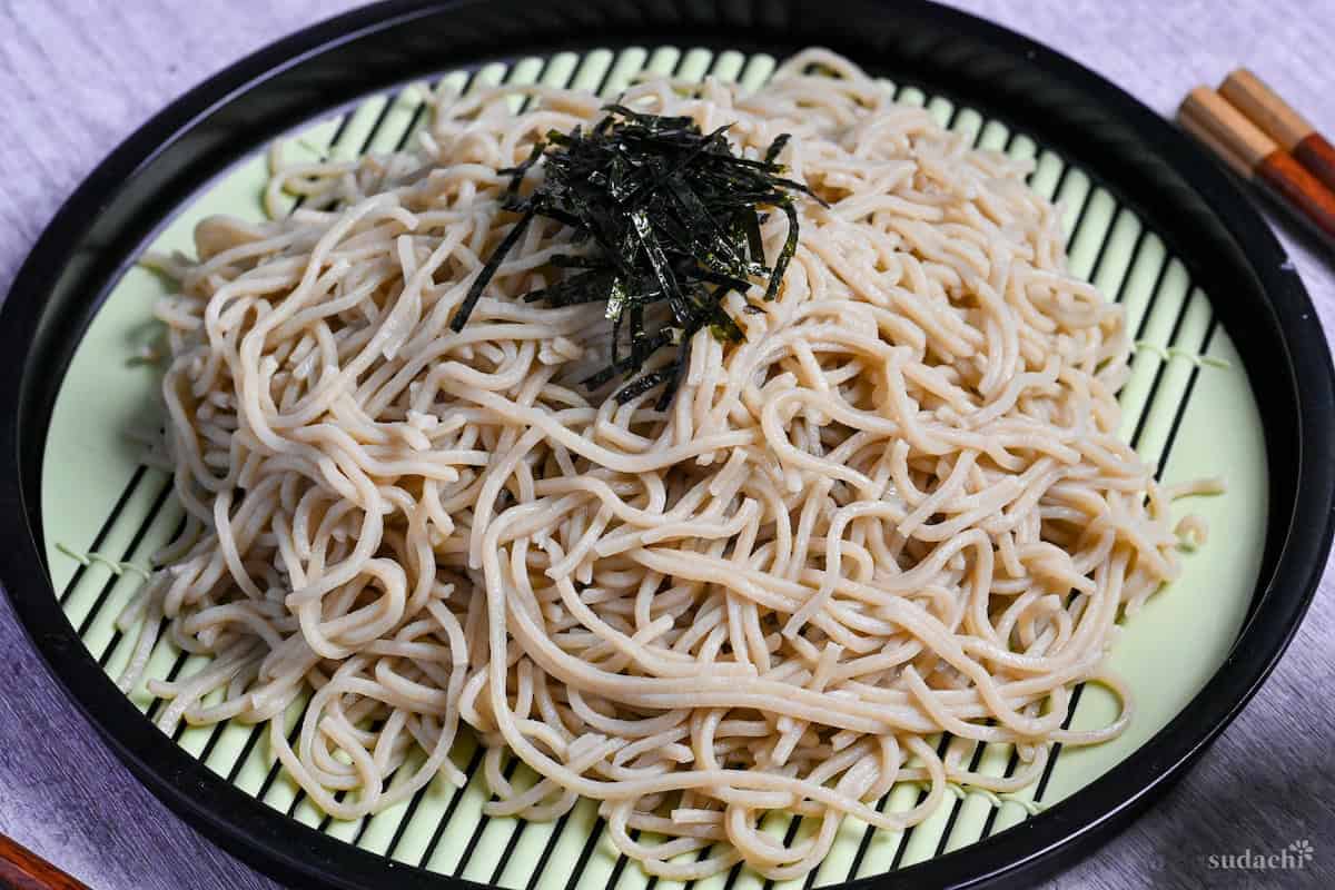 cooked homemade soba noodles on a zaru topped with shredded "kizami" nori to serve as zaru soba