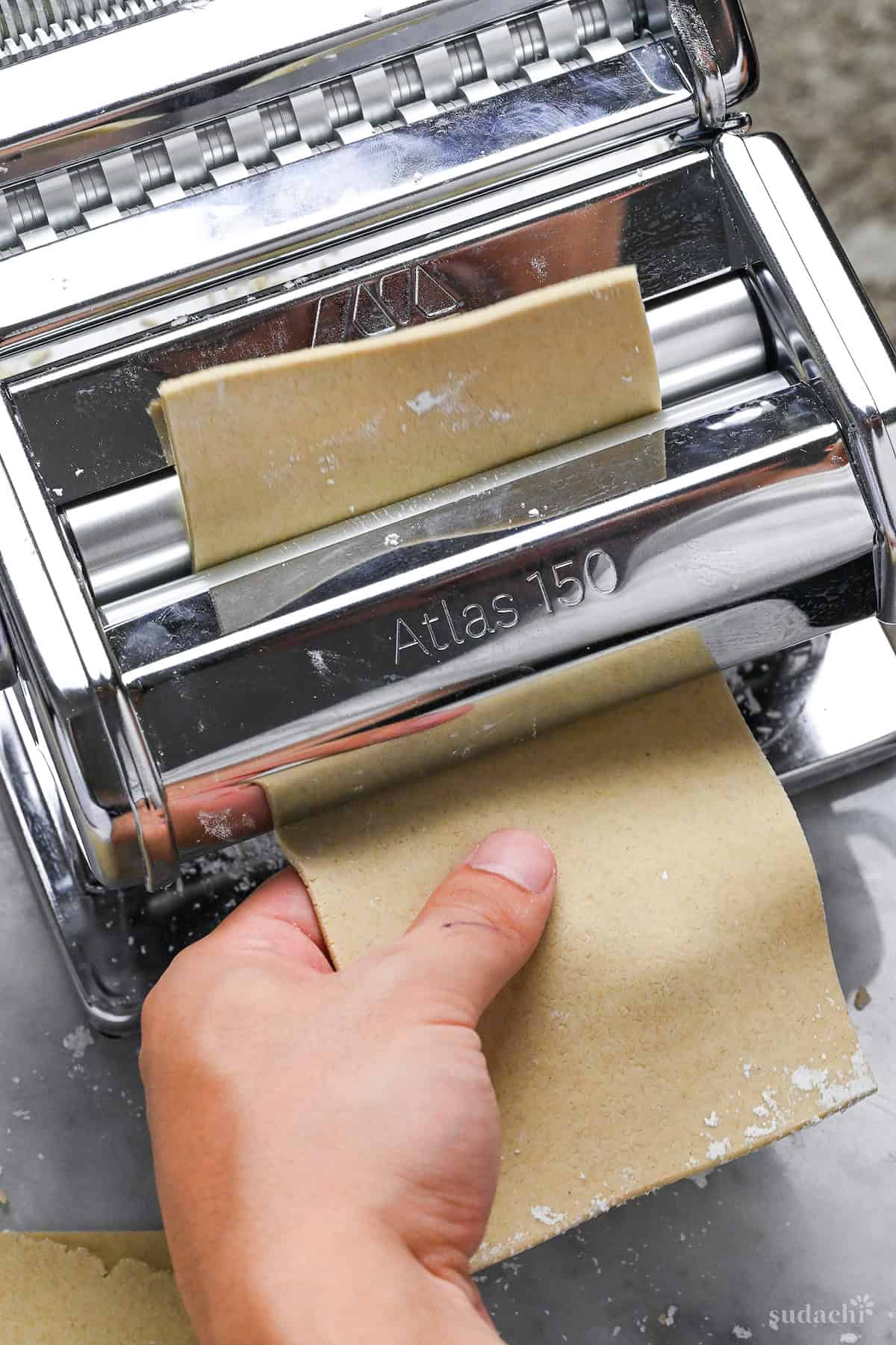 feeding rectangle of soba noodle dough through pasta machine