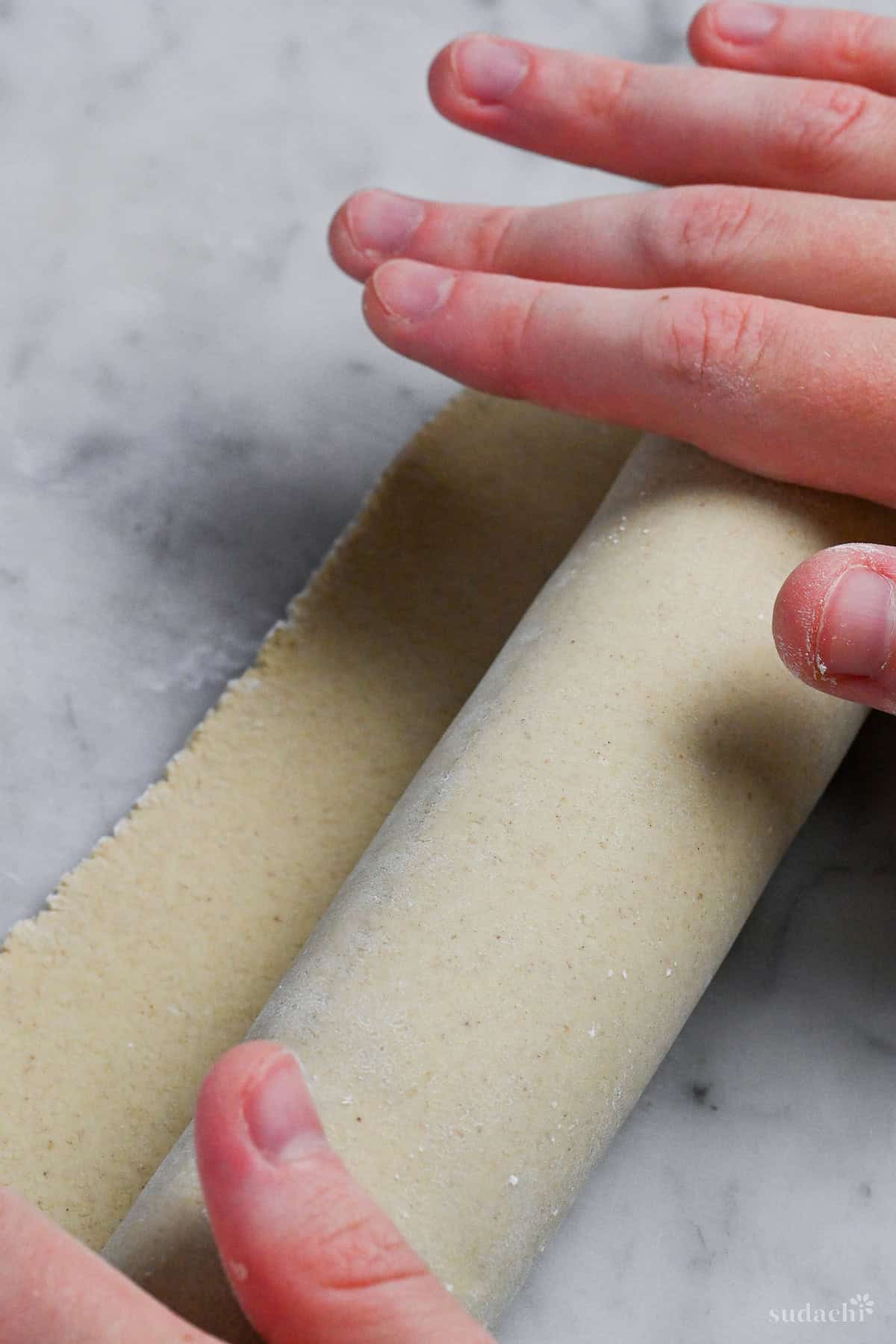rolling soba noodle dough onto a wooden rolling pin