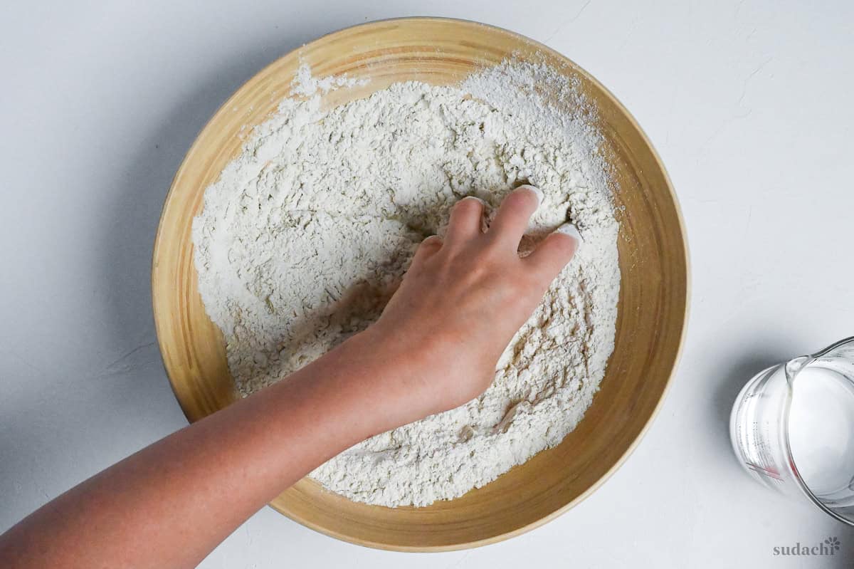 mixing water with soba flour by hand in a circular motion
